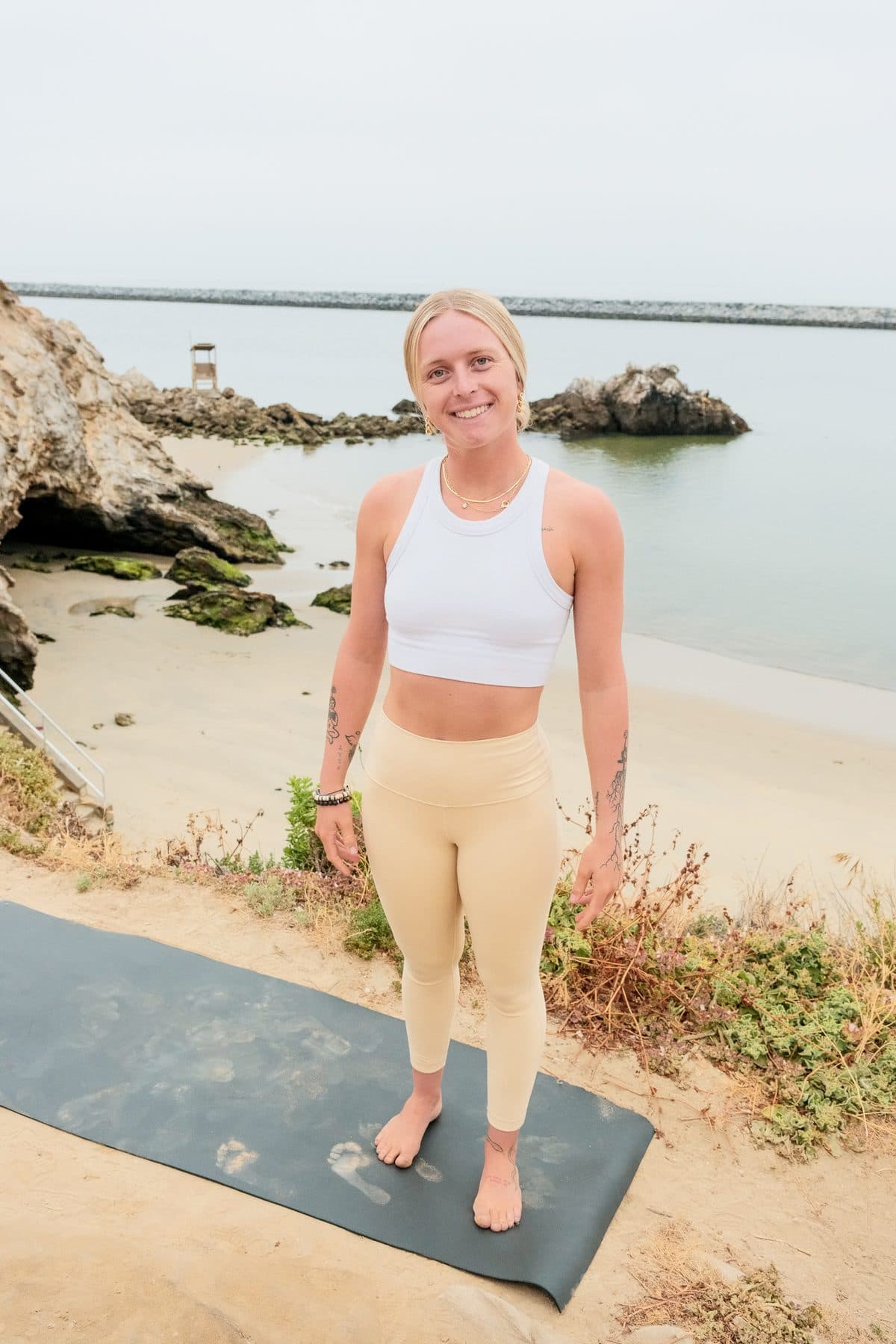 Coach Bella on a yoga mat by the ocean